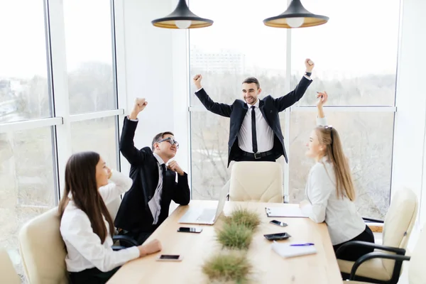 Zakelijke bijeenkomst. Mensen uit het bedrijfsleven in formalwear vieren overwinning samen aan tafel zittend — Stockfoto