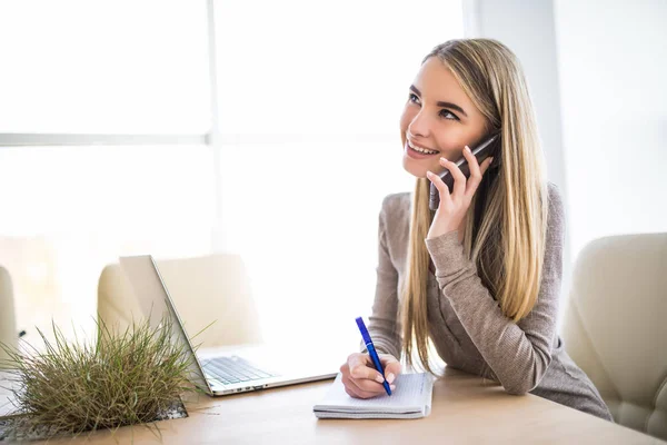 A fiatal üzleti nő portréja beszélni a telefon, és figyelje a notebook-on Hivatal — Stock Fotó