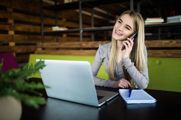 Fiatal nő beszélni a telefon, a munkahelyen. — Stock Fotó