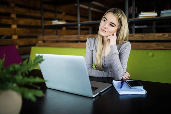 Mujer joven en el lugar de trabajo pensando y mirando hacia otro lado — Foto de Stock