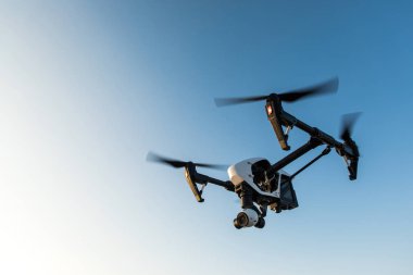 White drone with digital camera flying on sky background clipart