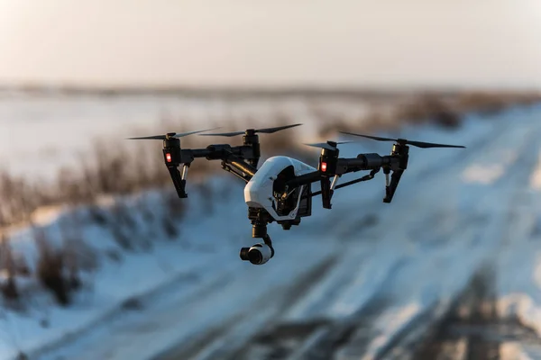 Weiße Drohne mit Digitalkamera fliegt und landet im Schnee — Stockfoto