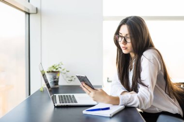 telefon ile ofiste oturan genç kadın işçi.