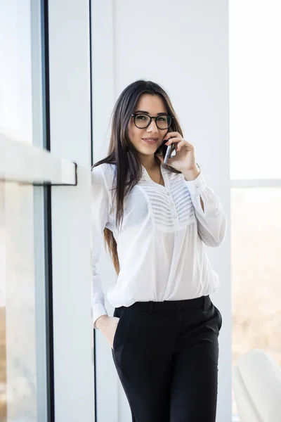 Business woman speak on phone near big office windows in modern smart space. — Stock Photo, Image