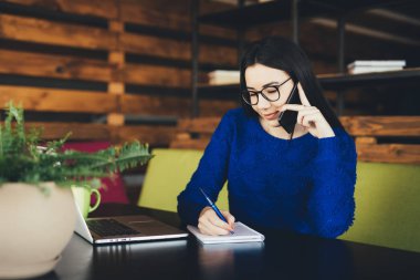 İş kadını telefonla konuşmak ve office hub çalışma masasında notlar