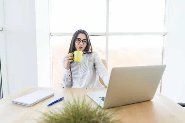 Joven dama de negocios beber café y mirar el ordenador portátil en la sala de conferencias — Foto de Stock