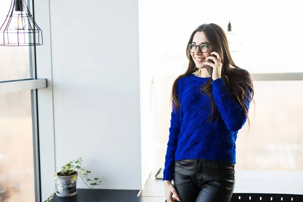 Fiatal nő beszél a modern iroda közelében windows telefon. — Stock Fotó