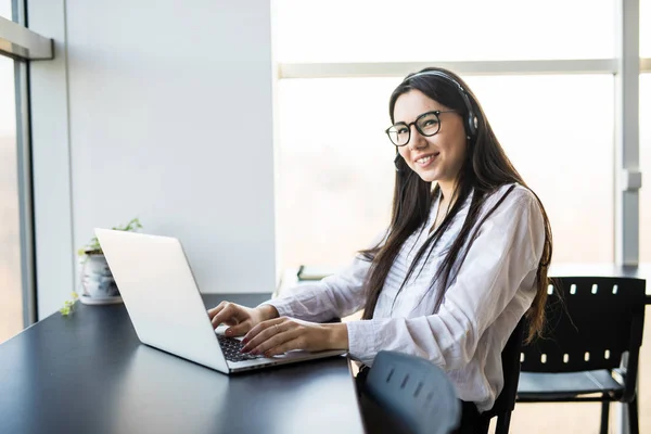 Mujer de negocios hablando por teléfono mientras trabaja en su computadora en la oficina — Foto de Stock