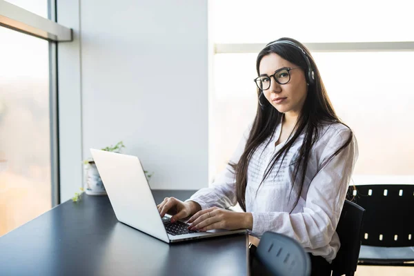 Affärskvinna prata i telefon medan du arbetar på hennes dator på kontoret — Stockfoto