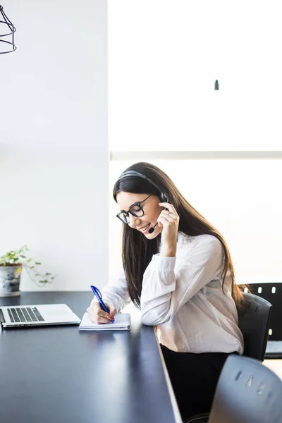 Femeie de afaceri cu căști în call center și să facă o notificare — Fotografie, imagine de stoc