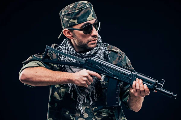 Ataque terrorista. Retrato de Terrorista com arma e óculos de sol sobre fundo escuro — Fotografia de Stock