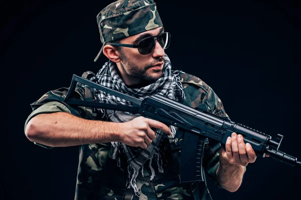 Terroristische atack. Portret van Terrorist met geweer en sunglases over de donkere achtergrond — Stockfoto