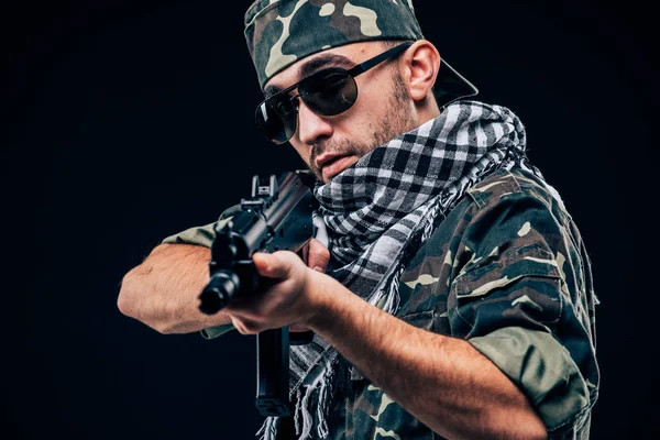 Ataque terrorista. Retrato de Terrorista com arma e óculos de sol sobre fundo escuro — Fotografia de Stock