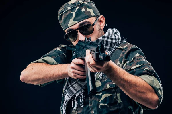 Ataque terrorista. Retrato de Terrorista com arma e óculos de sol sobre fundo escuro — Fotografia de Stock