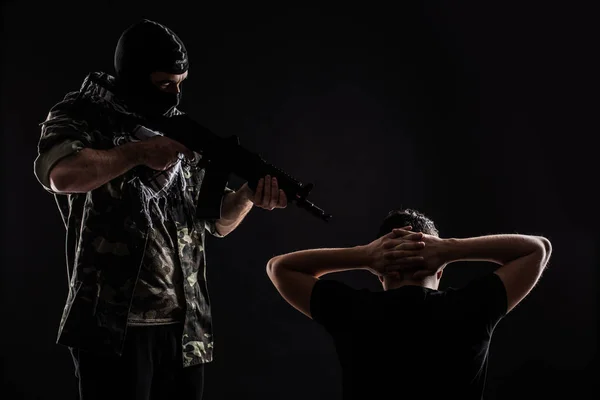 Terroriste avec arme à feu en otage sur fond noir — Photo