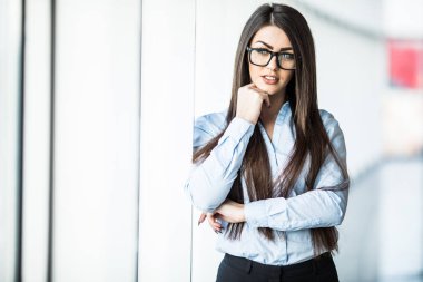İş kadını resmi giysiler ve panoramik pencerelere ofiste eyesglasses.