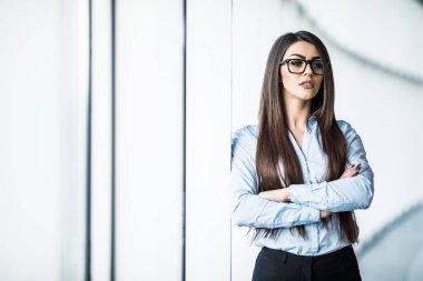 İş kadını resmi giysiler ve panoramik pencerelere ofiste eyesglasses.
