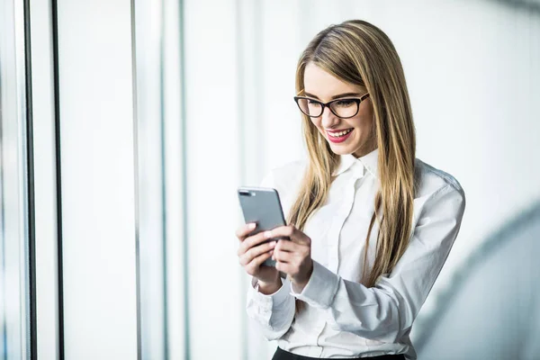 Zakelijke vrouw tekst sms op telefoon in moderne kantoren — Stockfoto