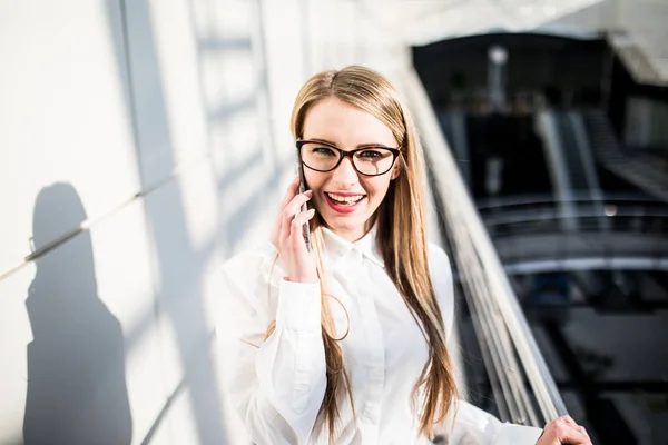 Молода жінка в офісі говорить на мобільному телефоні — стокове фото