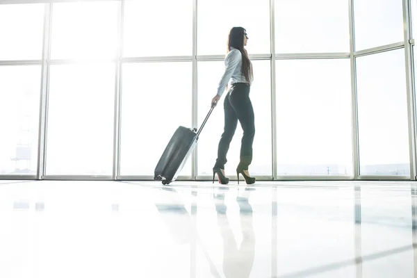 Business woman in airport running with baggage