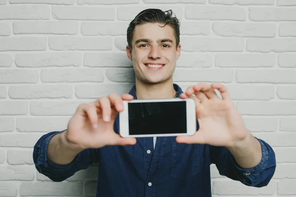 Piękny, młody człowiek w ubranie zrobić selfie na tle białym murem — Zdjęcie stockowe