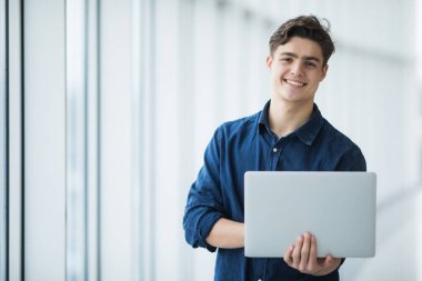 Yakışıklı genç adam bir dizüstü bilgisayar salonda holding