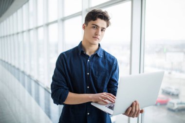 Yakışıklı genç adam bir dizüstü bilgisayar salonda holding