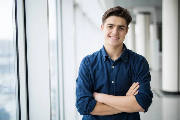 Retrato de un joven con las manos cruzadas cerca en la ventana . — Foto de Stock