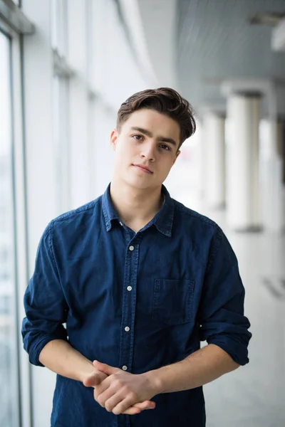 Retrato de un joven con las manos cruzadas cerca en la ventana . — Foto de Stock