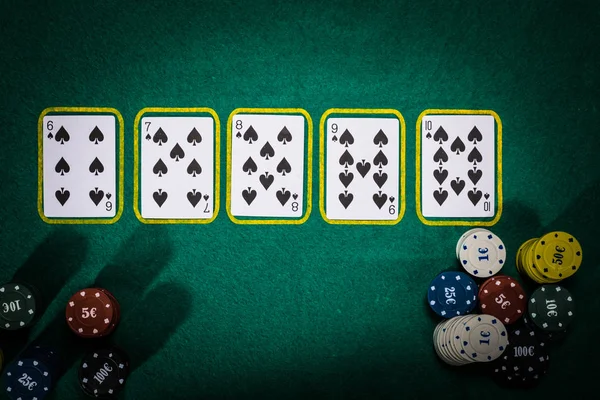 Pilha de fichas de cassino e royal flush baralho na mesa de poker verde