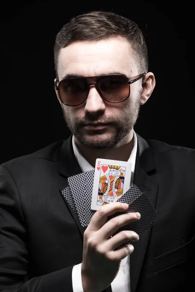 O jogador de poker em óculos pretos, em um cassino com uma carta aberta em um fundo preto . — Fotografia de Stock
