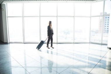 İş kadını havaalanında yürüyüş laggage çantalı