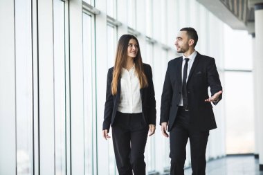 Ofiste yürüyen ve konuşan emin iş ortakları