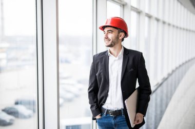 Kask ile kameraya gülümseyen dizüstü bilgisayar mühendisi.