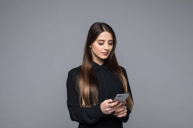 Cep telefonu gri arka plan karşı dururken tutan güzel genç iş kadını