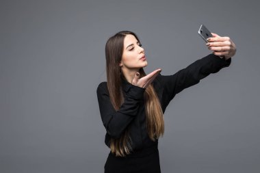 Selfie fotoğraf Smartphone'da yapma gülümseyen iş kadını. Gri arka plan üzerinde duran
