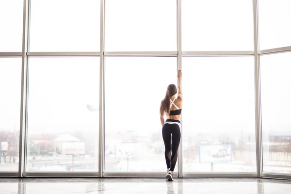Siluet gadis sporty sebelum pelatihan terhadap jendela panorama di gym — Stok Foto
