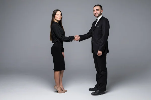 Zakelijke man en zakelijke vrouw handdruk en blik op de camera op een grijze achtergrond — Stockfoto