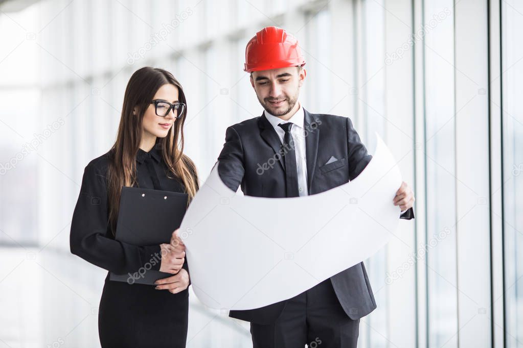 An attractive man and woman business team working construction on the building site near panoramic windows