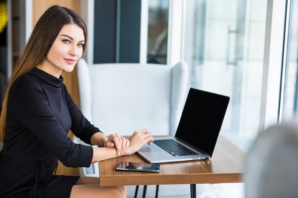 Vista lateral de una joven mujer de negocios utilizando el ordenador portátil en la cafetería — Foto de Stock