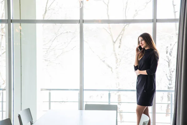 Giovane bella femmina con buon umore parlando sul cellulare smart phone con la sua amica mentre si rilassa nel caffè . — Foto Stock