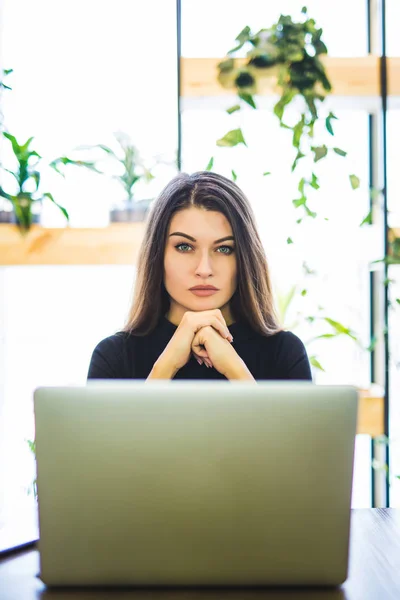 Retrato de atractiva mujer de negocios sentada en chait y trabajando en el ordenador portátil en línea . — Foto de Stock