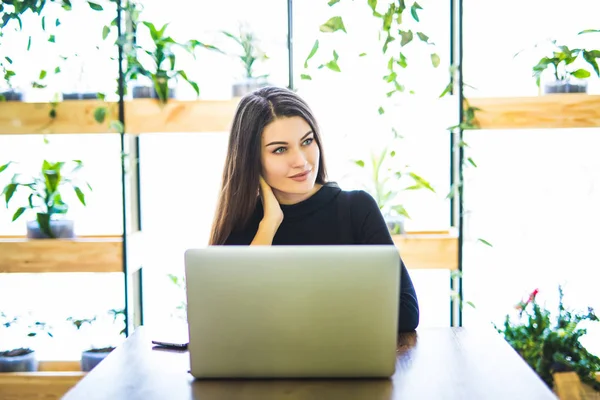 Retrato de atractiva mujer de negocios sentada en chait y trabajando en el ordenador portátil en línea . — Foto de Stock