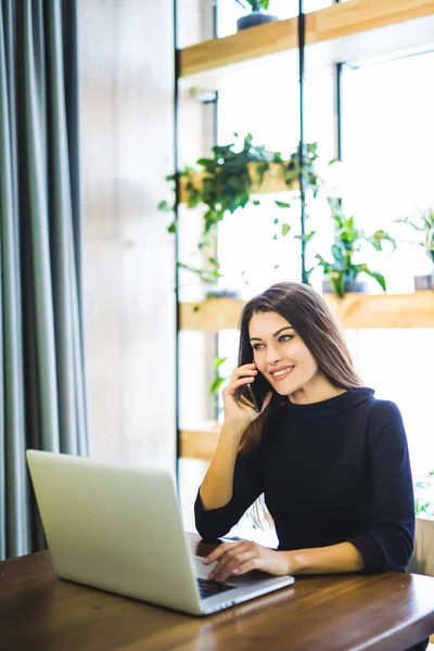 Prachtige vrouwelijke lijn bezig en praten over de telefoon en surfen een laptop thuis of op kantoor freelancer — Stockfoto