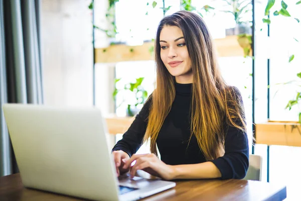 Frilansande kvinna sitter i cafeterian med laptop — Stockfoto