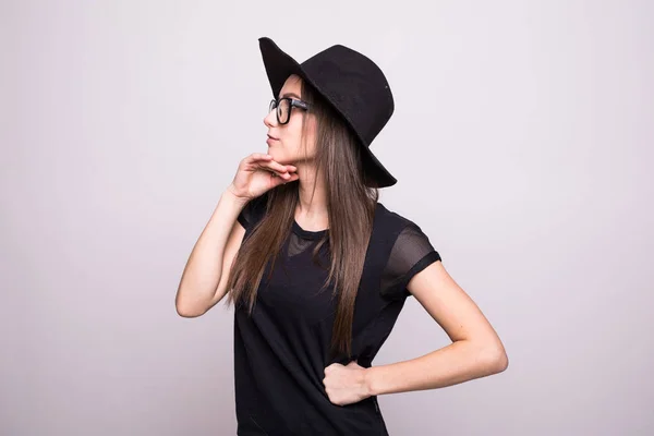 Νεαρή κοπέλα κάνει συγκίνηση. Ντυμένος με ένα μαύρο πουκάμισο, μαύρο καπέλο, γυαλιά στο studio — Φωτογραφία Αρχείου