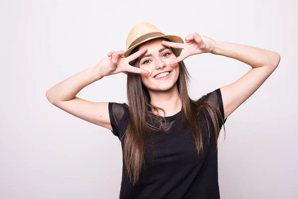 Fröhliches Mädchen mit Mütze macht Gesichter vor der Kamera auf grau — Stockfoto