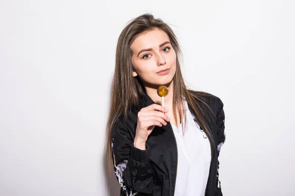 Joven hermosa chica comiendo chupa chups sobre fondo gris . —  Fotos de Stock