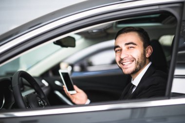 Araba kullanma smartphone ve gülümseme fotoğraf makinesinde işadamı