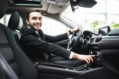 Araba ve araba paneli üzerindeki bazı düğme geçiş takım elbiseli genç adamın yakın çekim